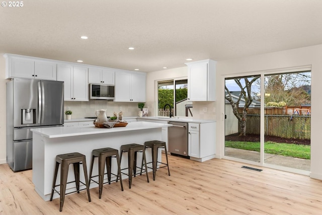 kitchen featuring visible vents, stainless steel appliances, light countertops, white cabinetry, and backsplash