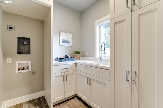 clothes washing area with cabinets, hookup for a washing machine, light hardwood / wood-style floors, hookup for an electric dryer, and sink