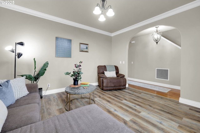 living room with hardwood / wood-style flooring, ornamental molding, and a chandelier