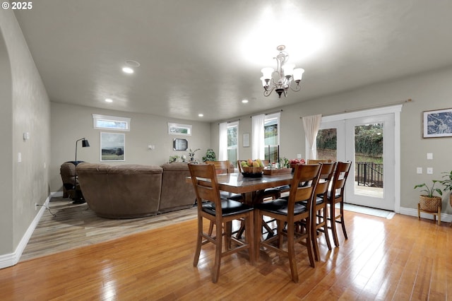 dining area with plenty of natural light, a chandelier, light hardwood / wood-style floors, and french doors