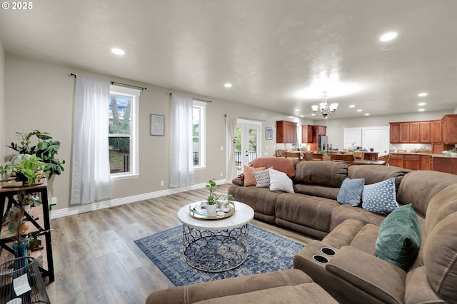 living room featuring plenty of natural light, light hardwood / wood-style flooring, and a notable chandelier