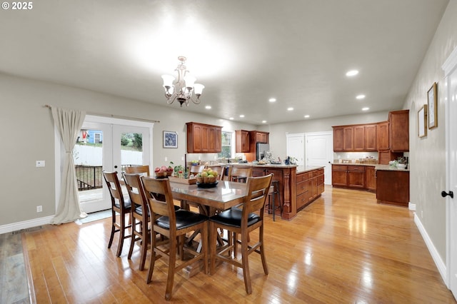 dining space with french doors, light hardwood / wood-style floors, and a notable chandelier