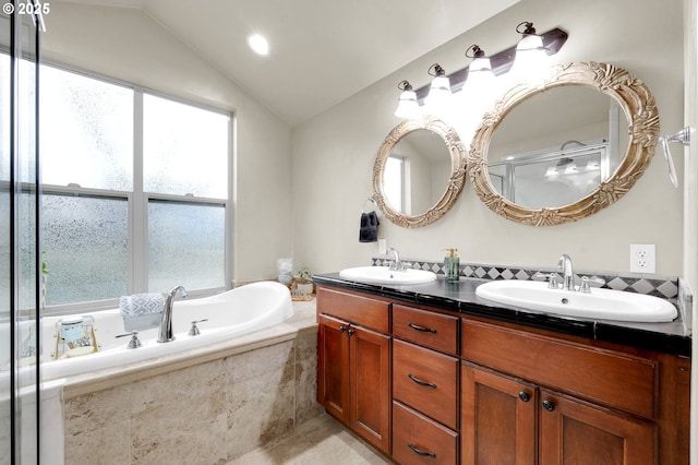 bathroom with lofted ceiling, vanity, and tiled tub