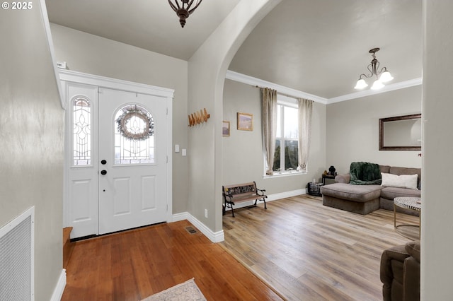 foyer with hardwood / wood-style flooring, crown molding, and a notable chandelier