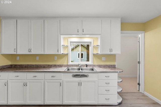 kitchen with light wood-type flooring, sink, and white cabinets