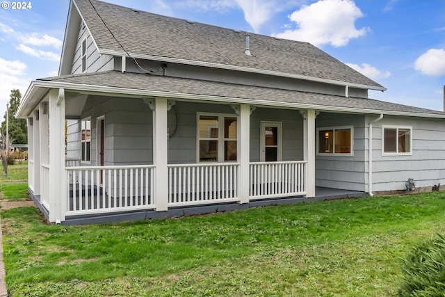 back of property with covered porch and a lawn