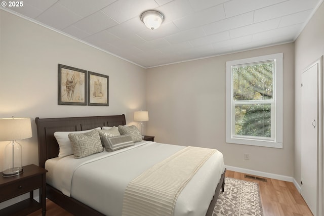 bedroom featuring crown molding and light hardwood / wood-style flooring