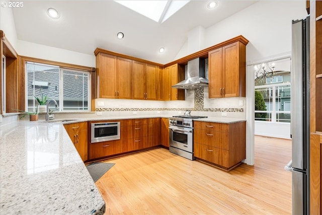 kitchen featuring lofted ceiling, sink, wall chimney exhaust hood, light stone countertops, and stainless steel range