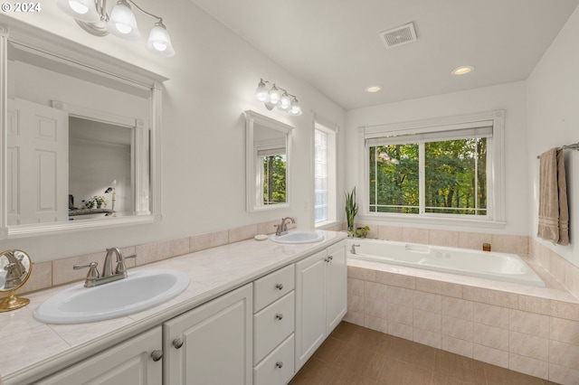 bathroom with tile patterned flooring, vanity, and tiled tub