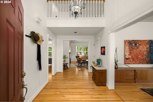 foyer with a towering ceiling, light hardwood / wood-style floors, and a notable chandelier