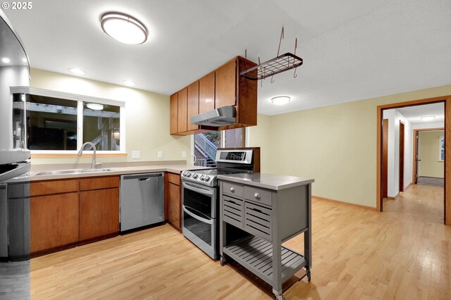 kitchen with sink, stainless steel appliances, and light wood-type flooring