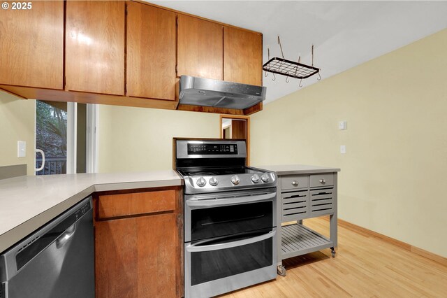 kitchen with stainless steel appliances, range hood, and light hardwood / wood-style flooring