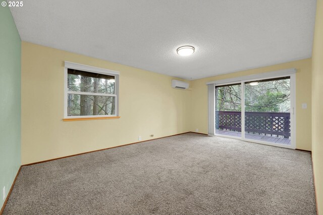 carpeted spare room featuring an AC wall unit and a textured ceiling