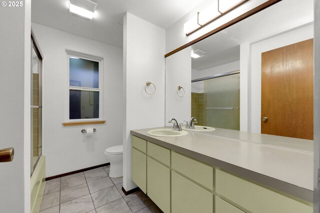 full bathroom with tile patterned flooring, bath / shower combo with glass door, vanity, and toilet