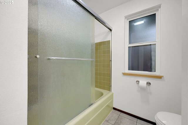 bathroom with toilet, tile patterned flooring, and combined bath / shower with glass door