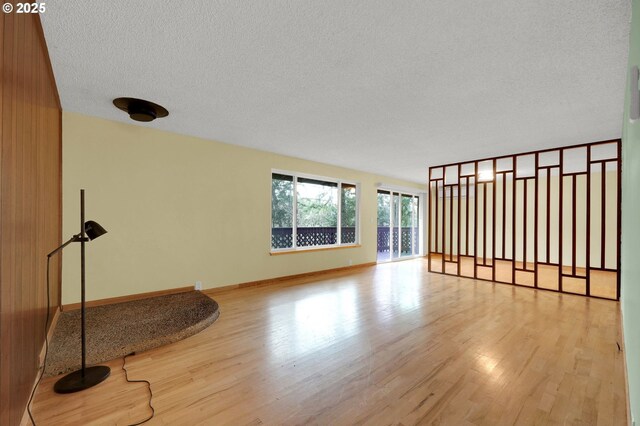 spare room with a textured ceiling and light hardwood / wood-style flooring