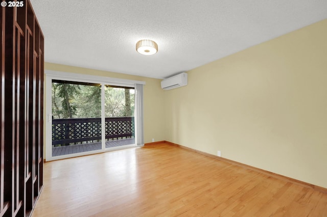 empty room with a textured ceiling, light hardwood / wood-style flooring, and an AC wall unit