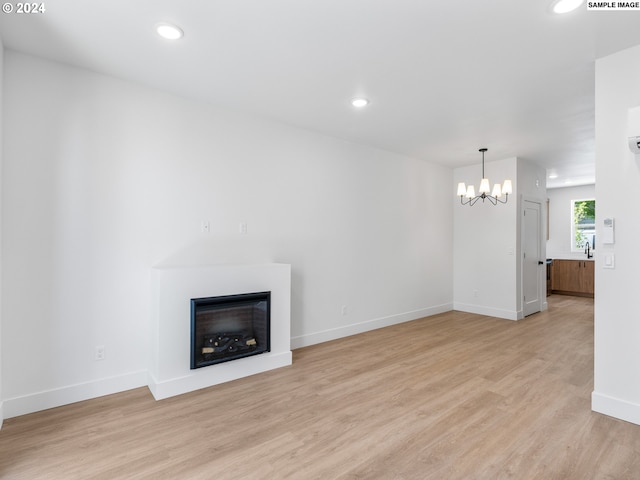 unfurnished living room featuring light wood-type flooring, an inviting chandelier, and sink