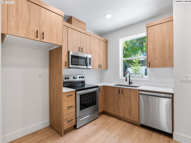 kitchen with light hardwood / wood-style floors, appliances with stainless steel finishes, sink, and light brown cabinets