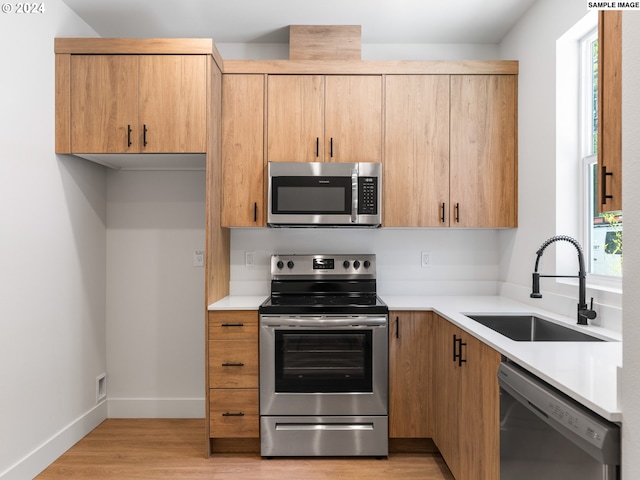 kitchen with light wood-type flooring, light brown cabinets, appliances with stainless steel finishes, and sink