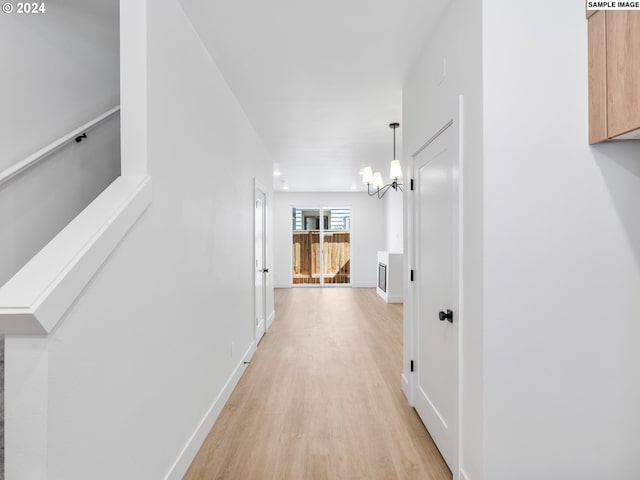 hallway with a notable chandelier and light hardwood / wood-style floors