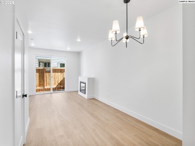 unfurnished room featuring a notable chandelier and light wood-type flooring