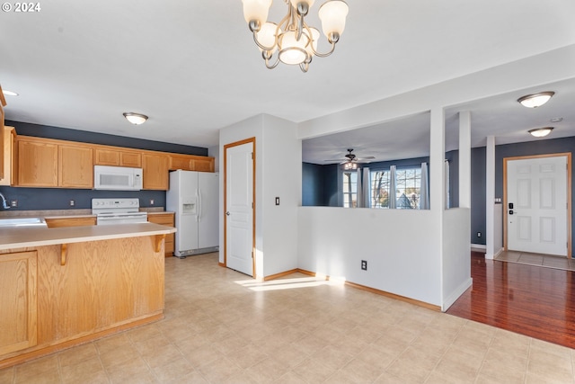 kitchen with a kitchen bar, white appliances, sink, pendant lighting, and light hardwood / wood-style flooring