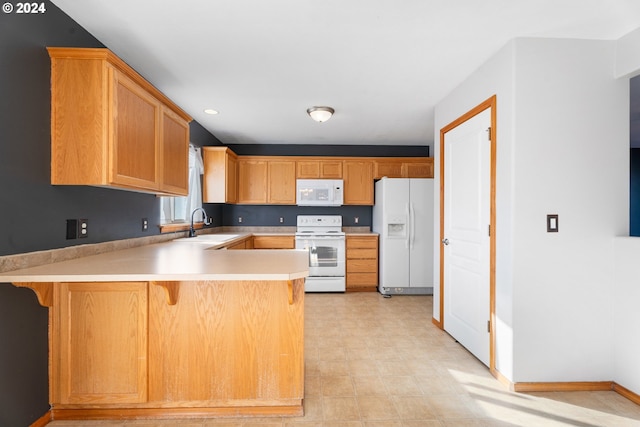 kitchen featuring a kitchen bar, kitchen peninsula, sink, and white appliances