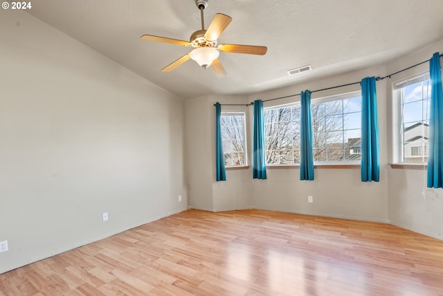 unfurnished room with ceiling fan, light hardwood / wood-style floors, a textured ceiling, and vaulted ceiling