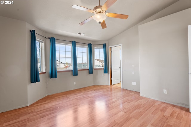 empty room with ceiling fan, light wood-type flooring, and vaulted ceiling