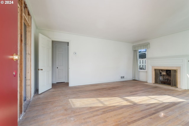 unfurnished living room with light wood-type flooring and crown molding