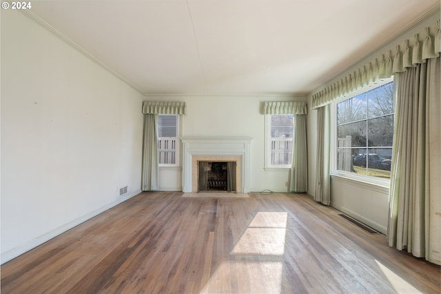 unfurnished living room featuring hardwood / wood-style floors and crown molding