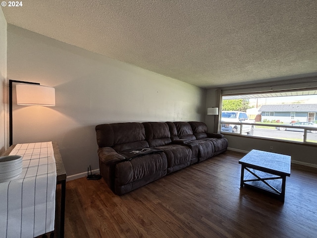 living room featuring a textured ceiling, baseboards, and wood finished floors