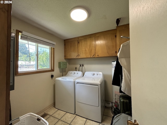 laundry area featuring light tile patterned floors, a textured ceiling, cabinets, and washing machine and dryer