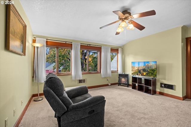 carpeted living room featuring a wood stove, a textured ceiling, ceiling fan, and a wealth of natural light