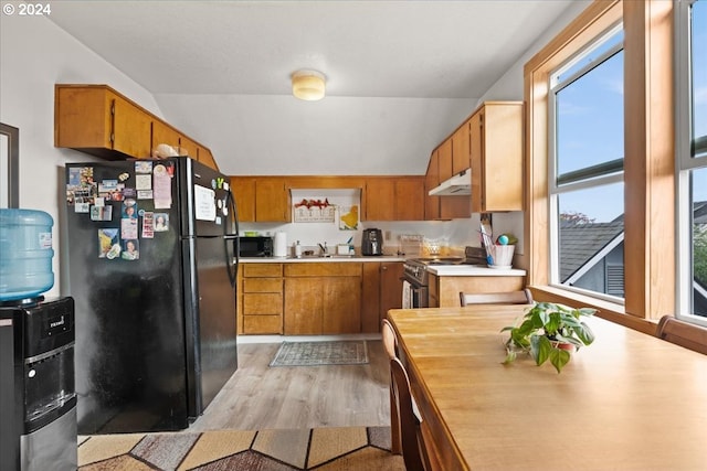 kitchen with sink, black appliances, lofted ceiling, and light wood-type flooring