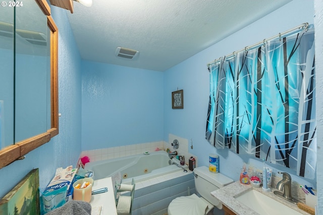 bathroom featuring tiled bath, toilet, a textured ceiling, and vanity