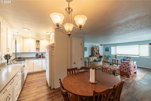 dining area with light hardwood / wood-style floors, a textured ceiling, and a notable chandelier