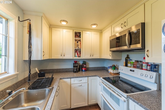 kitchen with a healthy amount of sunlight, sink, white cabinets, and range with two ovens