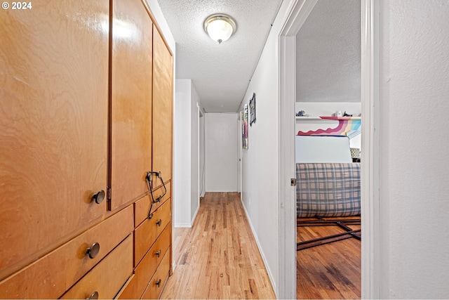 hall featuring a textured ceiling and light hardwood / wood-style floors