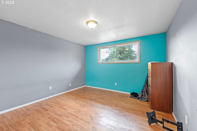 unfurnished room featuring wood-type flooring and a textured ceiling