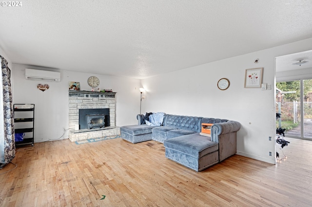 living room featuring a textured ceiling, a wall unit AC, and light hardwood / wood-style flooring