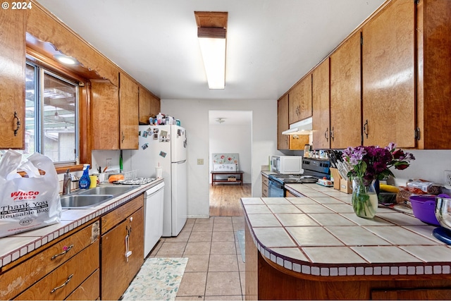 kitchen featuring tile counters, light tile patterned floors, white appliances, and sink