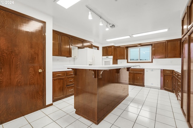 kitchen featuring a breakfast bar, a kitchen island, white appliances, and light tile patterned floors