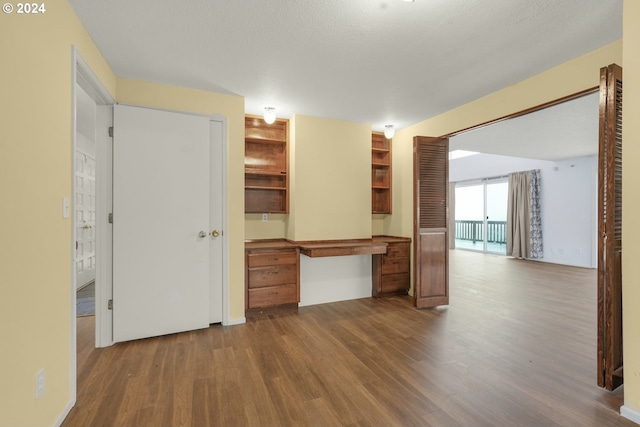 interior space with hardwood / wood-style flooring, built in desk, and a textured ceiling