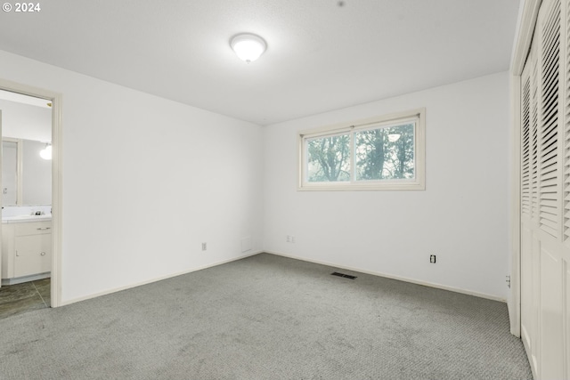 unfurnished bedroom with carpet flooring and ensuite bath