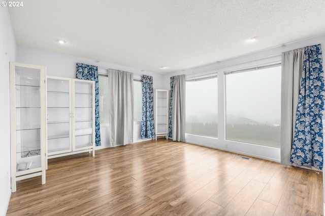 unfurnished room featuring wood-type flooring and a textured ceiling