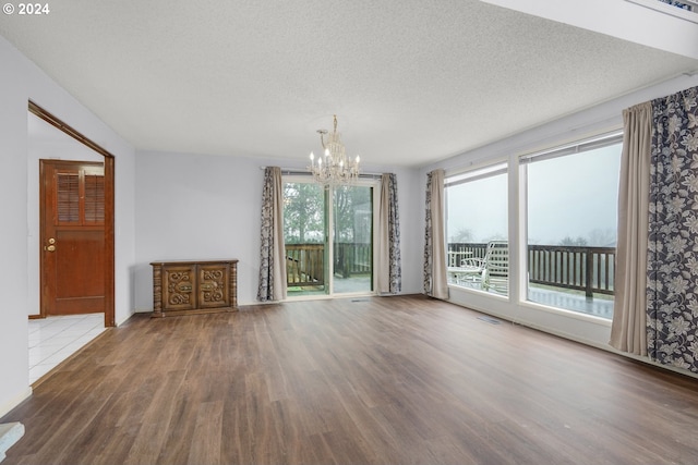 unfurnished living room with a textured ceiling, dark hardwood / wood-style floors, and a notable chandelier