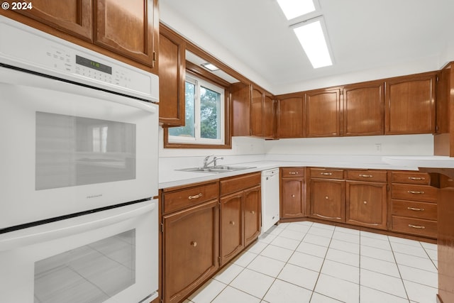 kitchen featuring sink, light tile patterned flooring, and white appliances