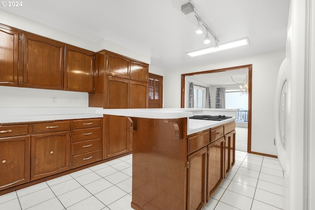 kitchen featuring track lighting, white appliances, light tile patterned floors, a notable chandelier, and a center island